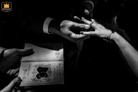   A bw close-up photo at a ceremony in Zuid Holland highlights the intricate details of hands as rings are exchanged, signifying the couple’s bond and promises.
